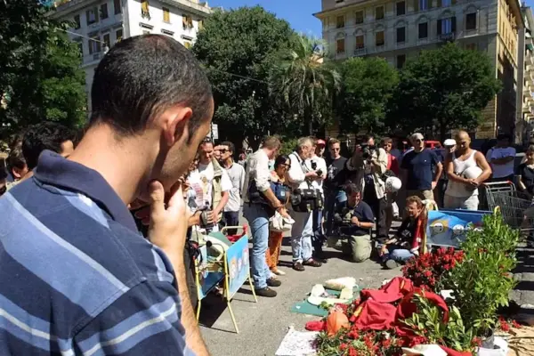 G8 Genoa: march in Piazza Alimonda, flowers and two fire extinguishers on plaque to Giuliani