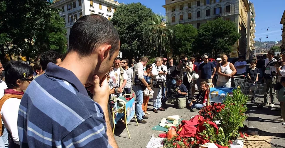 G8 Genoa: march in Piazza Alimonda, flowers and two fire extinguishers on plaque to Giuliani