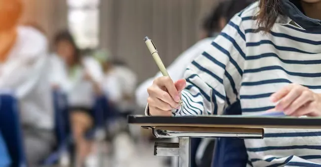 Exam at school with student's taking educational admission test in class, thinking hard, writing answer in university classroom, education and world literacy day concept Chinnapong - stock.adobe.com