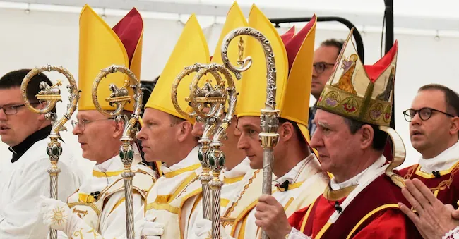 The newly consecrated bishops, from left: Pascal Schreiber, Michael Goldade, Michel Poinsinet de Sivry and Marc Hanappier, wearing mitres and holding pastoral staffs, pose at the end of the consecration ceremony in a tent set up outside the seminary of the Society of Saint Pius X in Écône, Switzerland, Wednesday, July 1, 2026. (Photo AP/Baz Ratner) APN