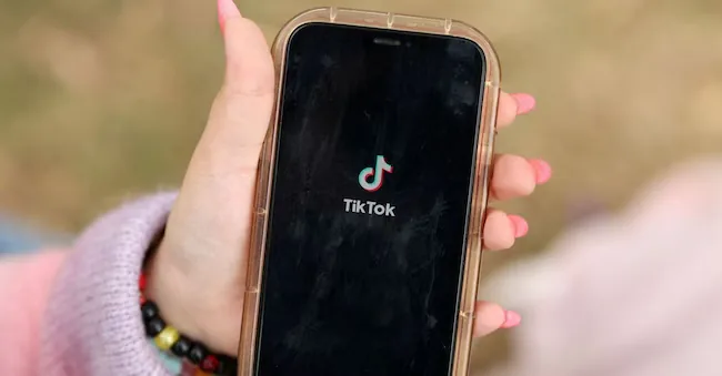 A girl poses while opening the TikTok app on her phone in Sydney, Australia, November 22, 2025. REUTERS/Hollie Adams/REUTERS file photo
