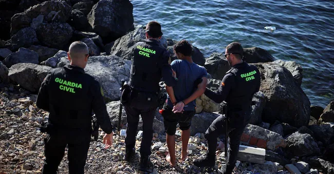 Members of the Spanish Guardia Civil stop a migrant during mass crossings on foot and by sea of migrants from Morocco to Spanish territory, in Ceuta. August 2, 2026. REUTERS/Pedro Nunes REUTERS
